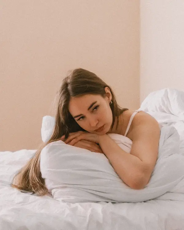 Femme pensive au lit illustrant l'anorgasmie — consultation sexologue à Strasbourg