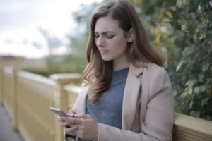 Femme soucieuse regardant son téléphone en attendant un message, peur de l'abandon, psychothérapie à Strasbourg et Lingolsheim